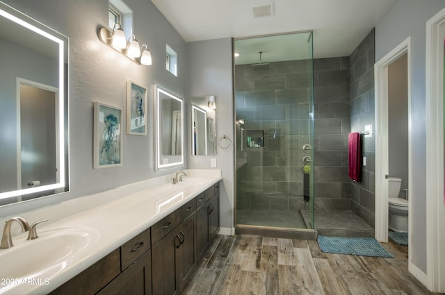 18175 W Highland Ave, Goodyear, AZ 85395 - bathroom with visible vents, wood finished floors, toilet, a sink, and a stall shower