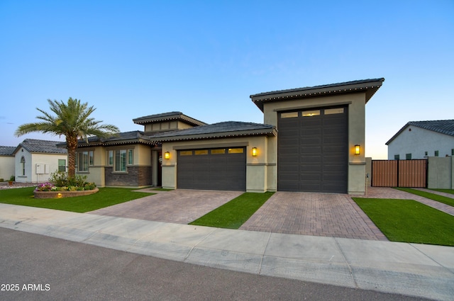 18175 W Highland Ave, Goodyear, AZ 85395 - prairie-style home featuring fence, a tile roof, a garage, stucco siding, and decorative driveway