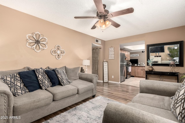 19258 N 20th Dr, Phoenix, AZ 85027 - living area featuring a textured ceiling, visible vents, baseboards, ceiling fan, and light wood-type flooring