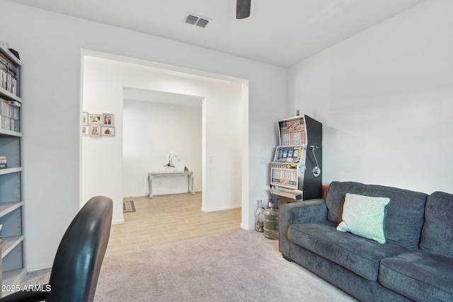 living room featuring carpet, visible vents, and a ceiling fan