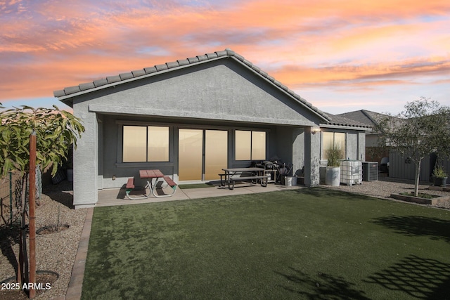 back of property featuring central air condition unit, stucco siding, a lawn, a patio area, and fence