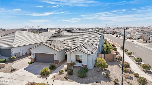 view of front of house with concrete driveway, a tile roof, a residential view, an attached garage, and stucco siding