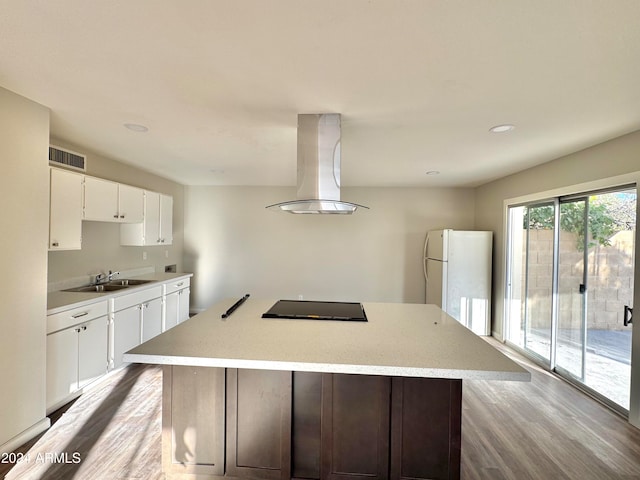 kitchen featuring black electric cooktop, white cabinets, light hardwood / wood-style floors, island range hood, and white refrigerator