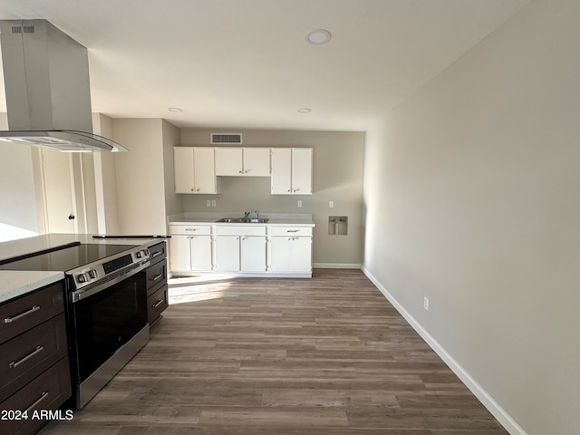 kitchen featuring wall chimney exhaust hood, wood-type flooring, white cabinets, and electric stove