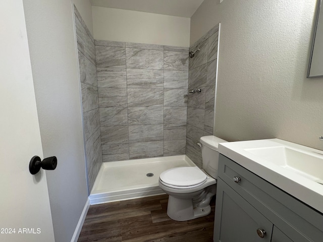 bathroom featuring vanity, hardwood / wood-style floors, toilet, and tiled shower