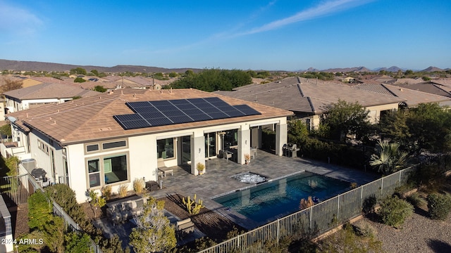 rear view of house with a mountain view, solar panels, a fenced in pool, and a patio area