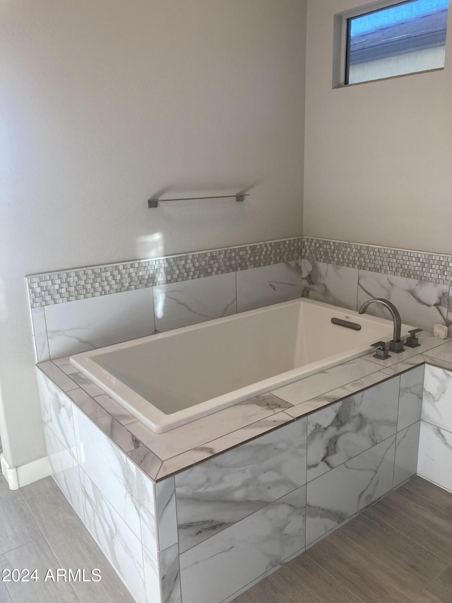 bathroom featuring hardwood / wood-style floors and a relaxing tiled tub