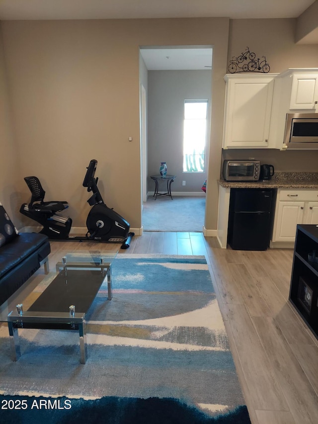 kitchen with stainless steel microwave, white cabinetry, and light wood-type flooring