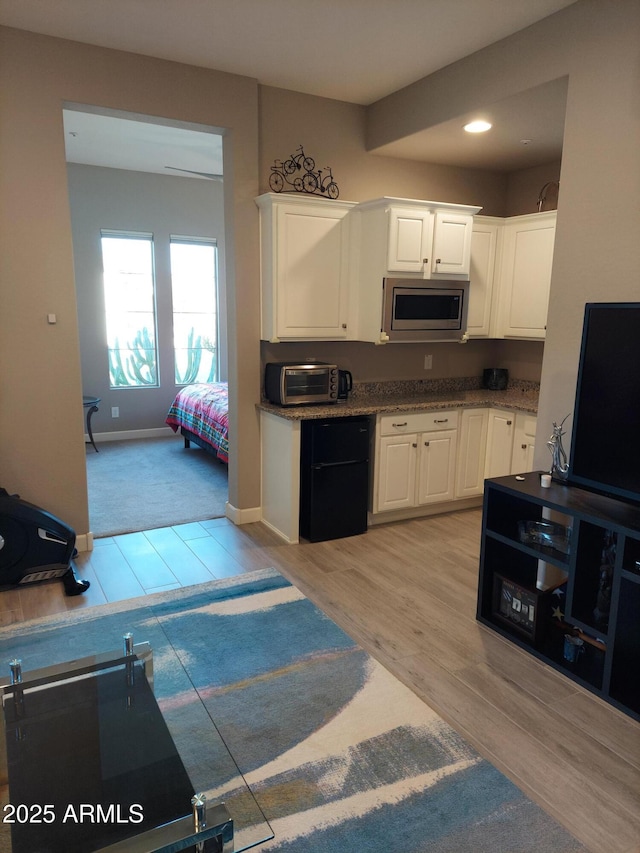 kitchen with white cabinets, light hardwood / wood-style floors, and stainless steel microwave