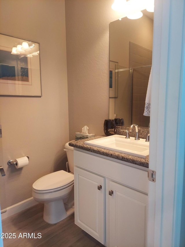 bathroom featuring toilet, a shower with door, vanity, and hardwood / wood-style flooring