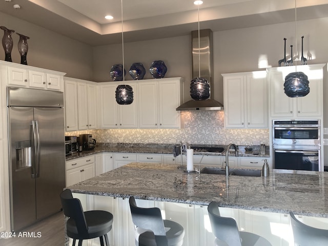 kitchen featuring sink, wall chimney exhaust hood, decorative light fixtures, white cabinets, and appliances with stainless steel finishes