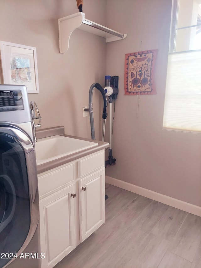 clothes washing area with cabinets, washer / dryer, light hardwood / wood-style flooring, and sink