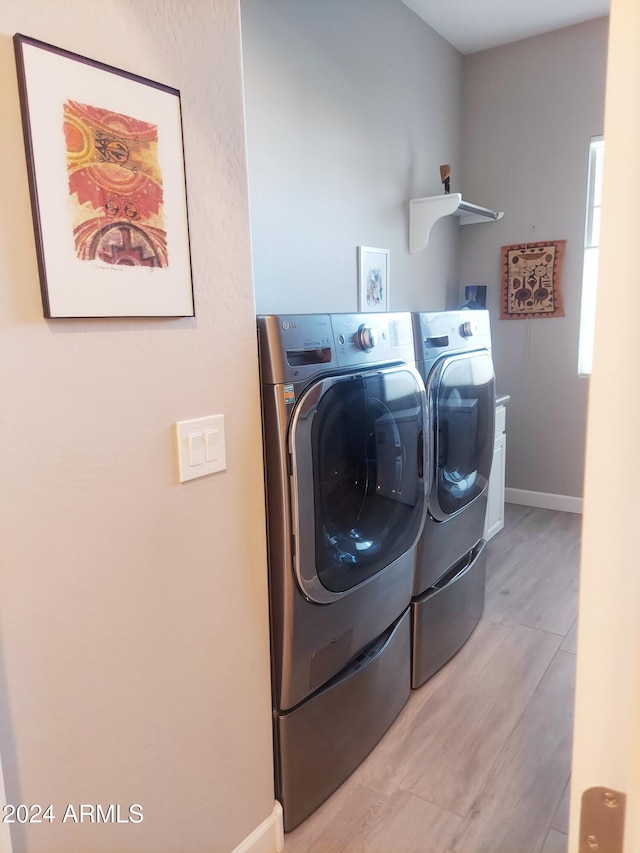 laundry room featuring washing machine and clothes dryer and light wood-type flooring