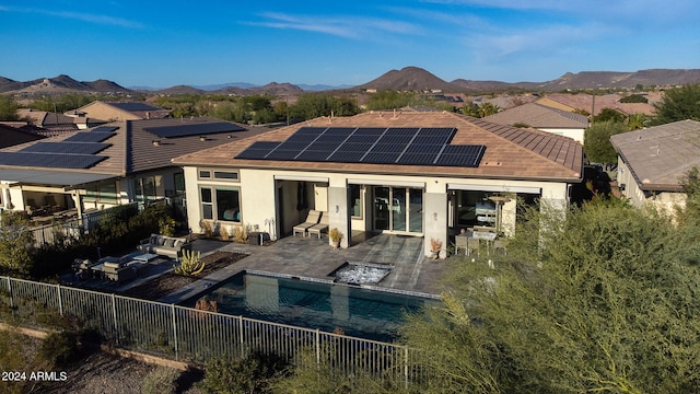 back of property featuring a mountain view, solar panels, a fenced in pool, an outdoor hangout area, and a patio