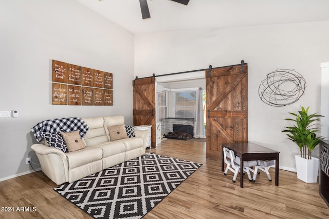 living room featuring a barn door, ceiling fan, hardwood / wood-style floors, and lofted ceiling