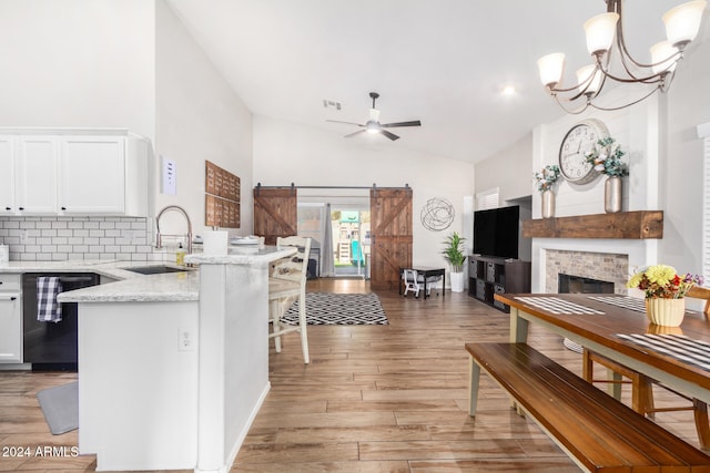 kitchen featuring dishwasher, sink, a barn door, light hardwood / wood-style flooring, and white cabinets