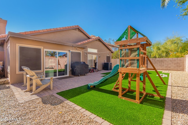 view of play area with a lawn, cooling unit, and a patio