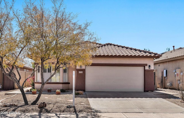 view of front of property with fence, driveway, an attached garage, stucco siding, and a tiled roof