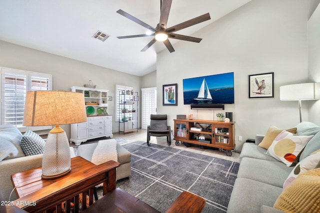 living room with a ceiling fan, a healthy amount of sunlight, visible vents, and high vaulted ceiling