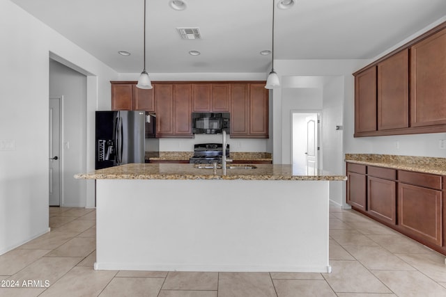 kitchen with appliances with stainless steel finishes, a center island with sink, light stone counters, and decorative light fixtures