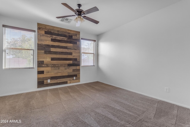 carpeted spare room featuring ceiling fan and wood walls