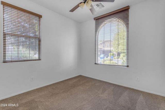 carpeted spare room with plenty of natural light and ceiling fan