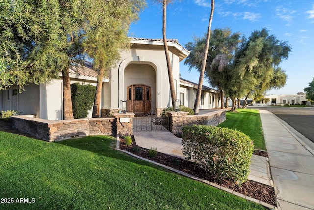 view of front facade featuring stucco siding, a front yard, and a tile roof