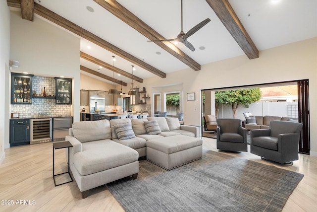 living room with ceiling fan, beverage cooler, beamed ceiling, bar, and high vaulted ceiling