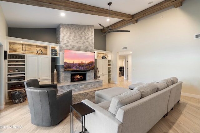 living room featuring light wood-type flooring, a fireplace, visible vents, and ceiling fan