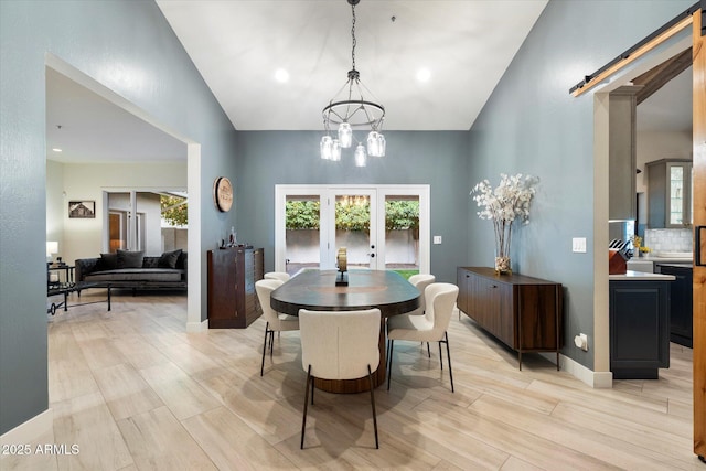 dining room with a chandelier, light wood finished floors, a wealth of natural light, and high vaulted ceiling