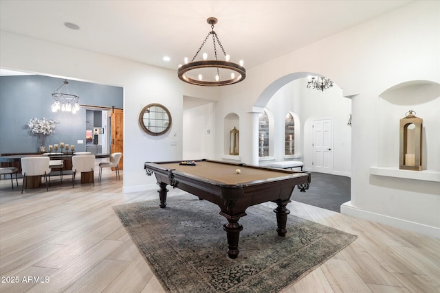 rec room with arched walkways, a notable chandelier, and light wood finished floors