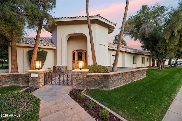 view of front facade featuring stone siding, stucco siding, a tile roof, and a yard