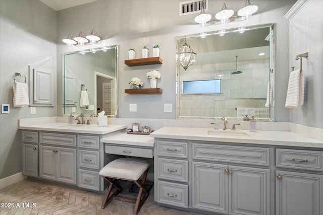 bathroom featuring vanity, visible vents, baseboards, a walk in shower, and a notable chandelier