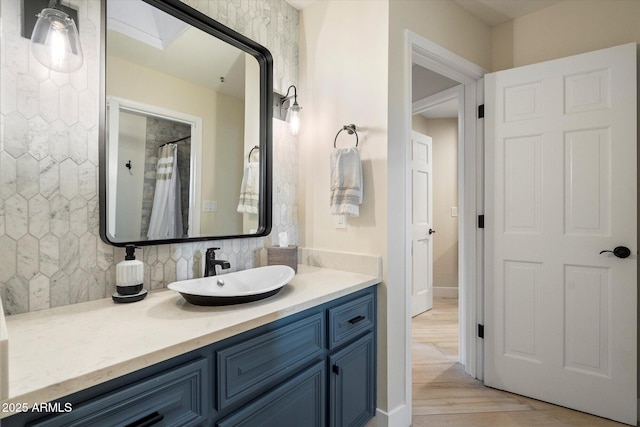 full bathroom featuring tasteful backsplash, wood finished floors, and vanity