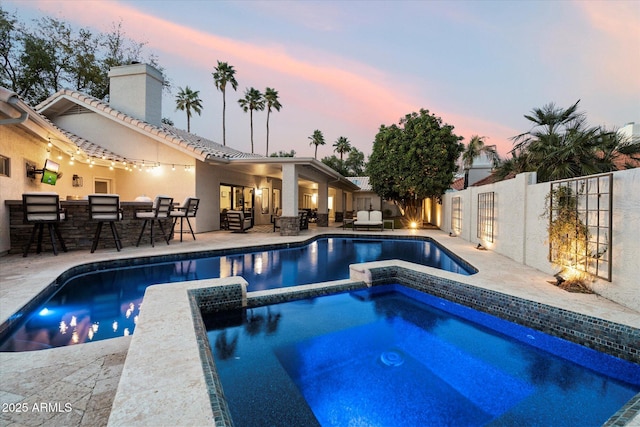 view of swimming pool featuring a fenced backyard, a patio, outdoor dry bar, and a pool with connected hot tub