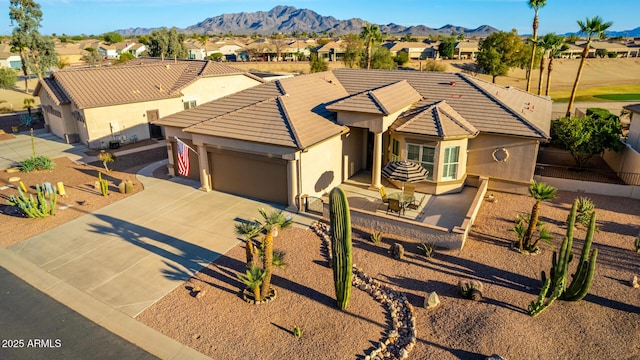 view of front of property featuring an attached garage, a mountain view, a tile roof, concrete driveway, and stucco siding