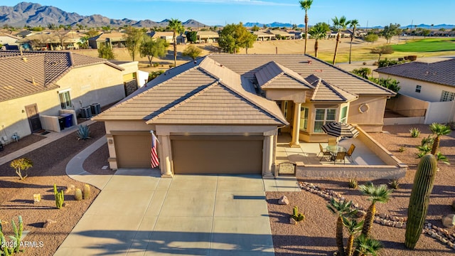 view of front of property featuring a garage, a tiled roof, concrete driveway, and a mountain view