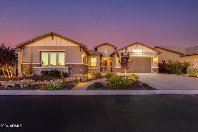 craftsman house featuring an attached garage, stone siding, a tiled roof, decorative driveway, and stucco siding