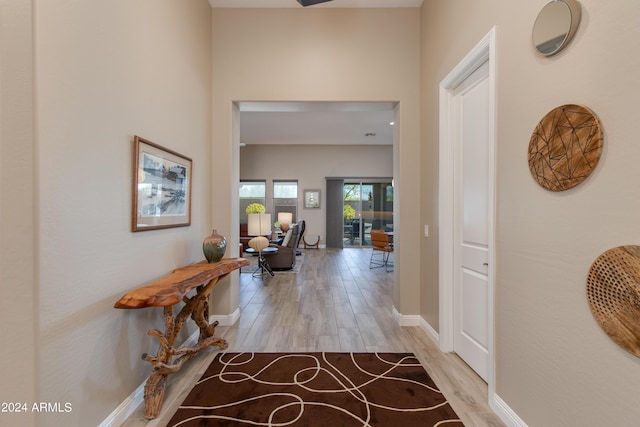 hall featuring light wood-style flooring and baseboards