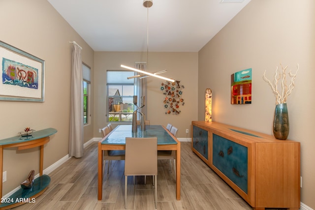 dining space featuring light wood finished floors, baseboards, and a notable chandelier