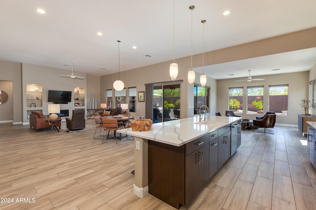 kitchen featuring open floor plan, light countertops, a sink, and light wood finished floors