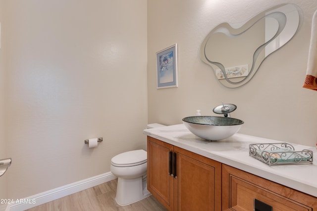 bathroom with vanity, wood finished floors, toilet, and baseboards