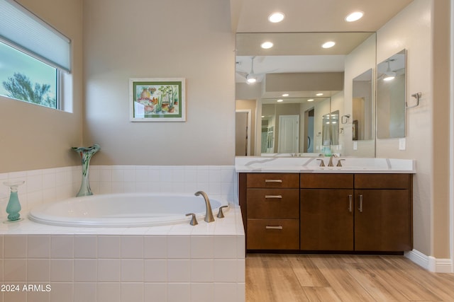 bathroom with a garden tub, vanity, and wood finished floors