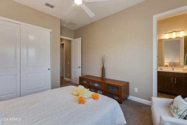 carpeted bedroom featuring a sink, visible vents, baseboards, a closet, and ensuite bath