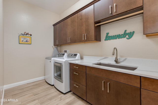 washroom with cabinet space, a sink, light wood-type flooring, independent washer and dryer, and baseboards