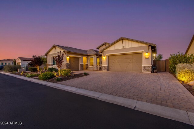 view of front of house featuring a garage, stone siding, decorative driveway, and board and batten siding