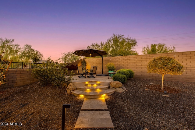 yard at dusk featuring a patio area and a fenced backyard