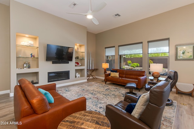 living room featuring visible vents, wood finished floors, and a glass covered fireplace