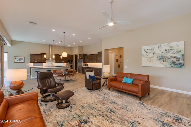 living area with light wood-style floors, visible vents, ceiling fan, and baseboards