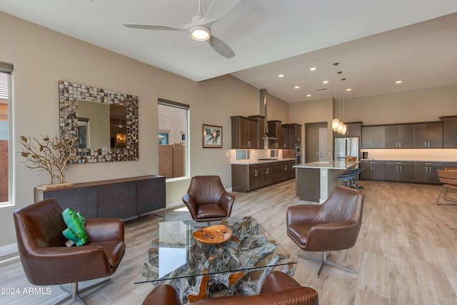 living room featuring ceiling fan, baseboards, light wood-style flooring, and recessed lighting